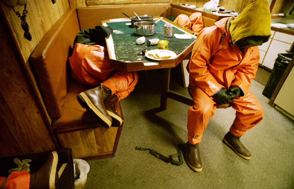 Exhausted crewmen crash in the galley of the fishing vessel Polar Lady while their boat travels to the next string of pots. Crabbers sleep four to six hours a night, less when the fishing is good. They work seven days a week for several months. There is no such thing as sympathy on a crab boat. With only a crew of five or six men, the sick or injured can't go to bed and recuperate. Crabbers often exist on one hot meal, sandwiches, candy bars, sodas, and a staple of ibuprofen and flu medicines. The Bering Sea is known for having the worst storms in the world. Crab fishing in the Bering Sea is considered to be one of the most dangerous jobs in the world.  This fishery is managed by the Alaska Department of Fish and Game and is a sustainable fishery. The Discovery Channel produced a TV series called {quote}The Deadliest Catch{quote} which popularized this fishery. © copyright Karen Ducey