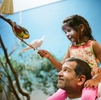 Sara Hussaini, age 6, and her father Akbar Hussaini from Austin, Texas feed Australian parrots seeds on a stick at the Woodland Park Zoo. This display features more than 150 parrots in a 1,200 square foot space. This collection of birds features budgerigars (parakeets), cockatiels, and rosellas. These species are abundant in Australia's though the zoo points out other parrot species are at risk. (photo Karen Ducey)