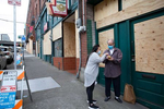 Lisa Chan, a doctor from the International Community Health Services, which is based in the Chinatown-International District, explains to Guofu Cao the directions on a bottle of Vitamin C and why its important for him to take it, outside his apartment in Seattle, Washington on June 4, 2020. Chan delivered groceries to some of her patients on her day off as a way of checking in on them. Storefronts throughout the Chinatown-International District were boarded up after riots came through their neighborhood. Riots occurred nationwide over the death of George Floyd who died while in the custody of a white policeman in Minneapolis.