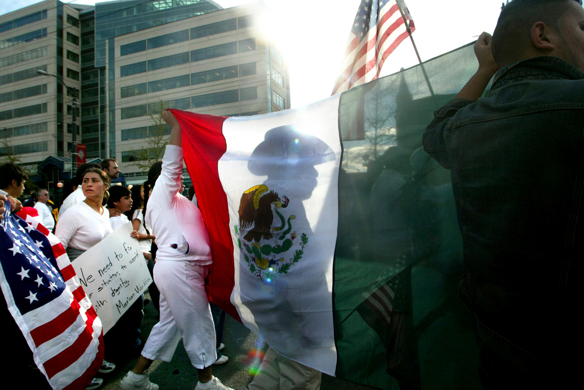 A man who didn't want to give his name, marches in front of a Mexican flag with 15,000 others in Seattle during a rally for immigration rights on April 10, 2006.  Asking for amnesty, equal rights, open borders, recognition and respect they demonstrated in solidarity with hundreds of thousands across America demanding immigration reform. 