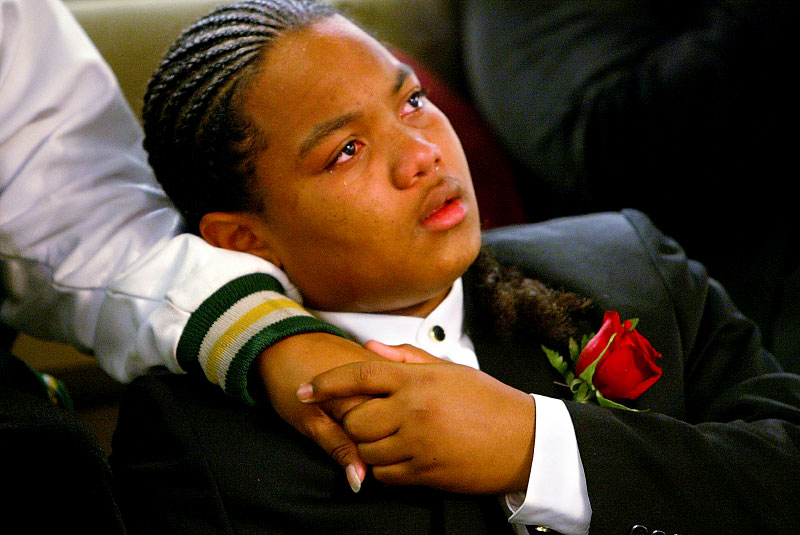 {quote}THIS IS NO JOKE.  THIS IS MY LIFE{quote}  Jordan Jantoc holds the hand of his mother, Lena Jantoc, during his brother’s funeral. Several weeks ago he had accidentally shot his brother while the two were playing with a handgun in the family's home.  The two had been the best of friends and were often referred to in unison as “Michael Jordan.” Charged as an adult he faces up to 8 years in prison.  On home detention he is in a prison of his own surrounded by his family and his guilt.  The first sentence of his online My Space page reads “This is not a joke.  This is my life”.   This is the first story in a six part multimedia series photographed between 2005-2006. It was nominated for a Pulitzer Prize. © Karen Ducey/Seattle PI