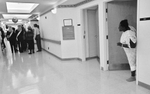 A hospital patient peers out her door to check out all the fuss in the hallway as several Miss USA delegates and their entourage make a PR stop at Methodist Hospital in Gary, Indiana.  (© Karen Ducey 2001)
