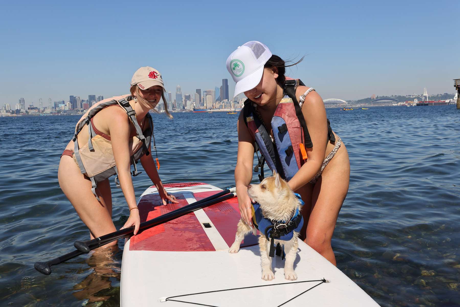 Mei Vandervelde (R) and Dayne Smith take their Husky puppy dog wearing a life vest out on a paddleboard in Elliott Bay during a heat wave in Seattle, Washington, U.S., June 27, 2021. REUTERS/Karen Ducey