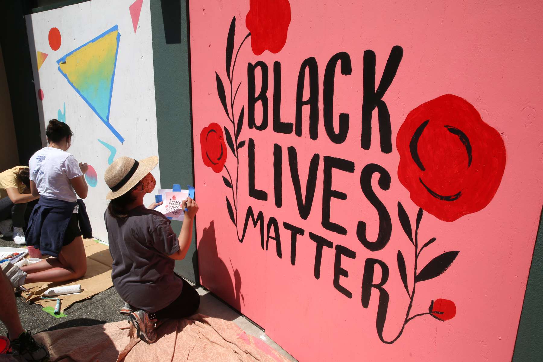 Misha Zadeh and Ben Graham (not in photo) paint a Black Lives Matter mural on the boarded up ICHS Vision Clinic in Seattleís Chinatown International District in Seattle Washington on June 14, 2020. Says Zadeh, {quote}Its really cool to see the arts community come together and put effort into such a good cause.{quote} Several community arts events were held to beautify the boarded up storefronts and support the Black Lives Matter movement. (Photo by Karen Ducey)