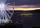 Seattle's Great Wheel with a passing ferry behind at twilight in.