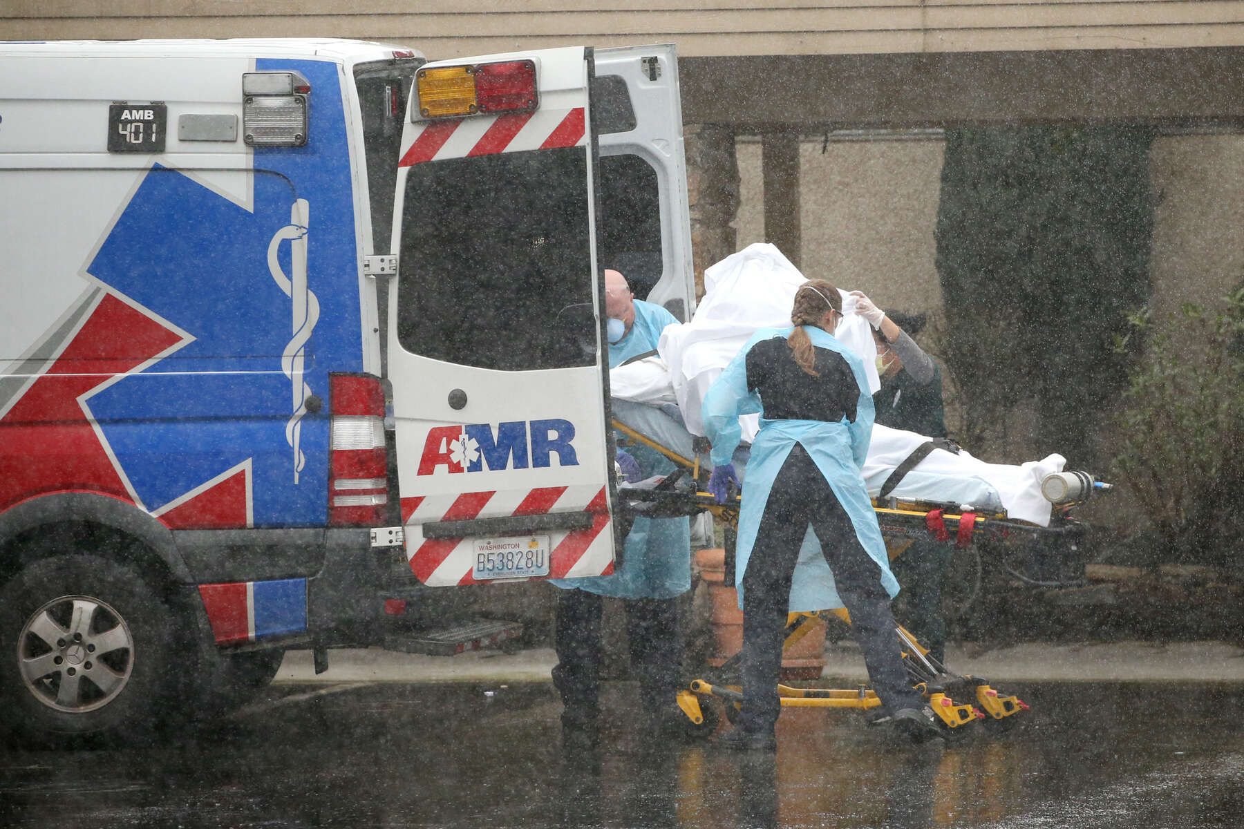 KIRKLAND, WA - MARCH 07: A patient is shielded from the rain as they are put into an ambulance outside the Life Care Center on March 7, 2020 in Kirkland, Washington. Several residents have died from COVID-19 and others have tested positive for the novel coronavirus. (Photo by Karen Ducey/Getty Images)