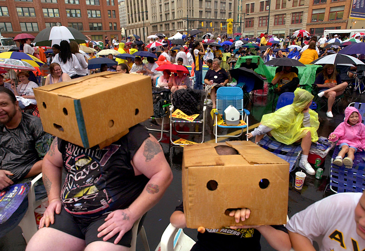 Fred Drake (left) and Aaron Drake (right), age 11, use boxes to shield their heads during the heavy rains which drowned Pacers fans prior to Game 4 of the NBA Finals.  The large screen viewing party across the street from Conseco Fieldhouse attracted thousands of people despite the poor weather. (© Karen Ducey/Indianpolis Star)