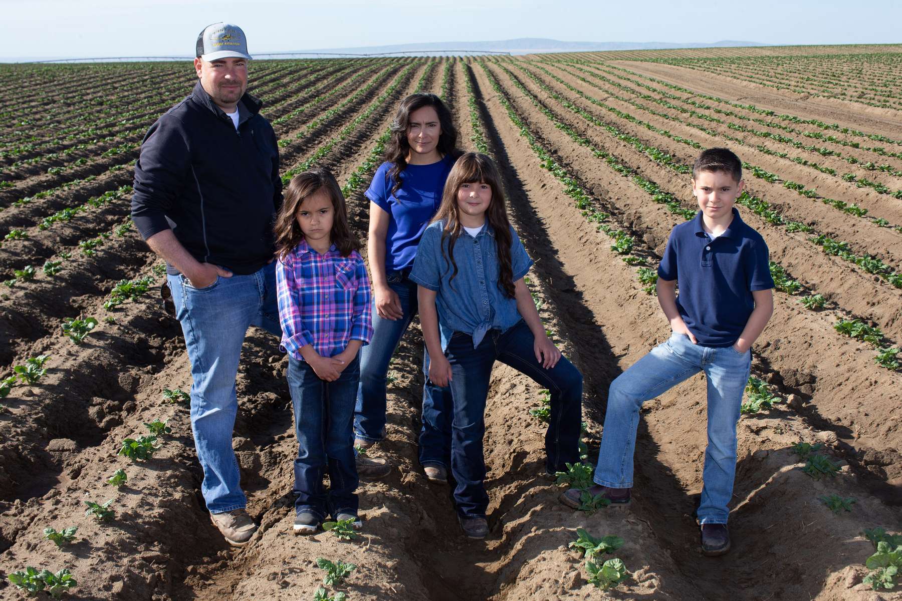 From left to right: Jordan Reed, Breanna, 5 years Mia, Addison, 8, and Owen, 10 pose in a neighbor’s potato field in Pasco, Washington on May 1, 2020. A billion pounds of excess potatoes in Washington state, second largest potato producer in the country. About 70 percent of its crop usually goes to overseas, to Pacific Rim countries primarily, in the form of french fries, but with so many restaurants/food service closed in U.S. and internationally, they have way more potatoes than they can sell. Last year they didn’t have enough to meet demand; now growers are facing the prospect of losing it all. (photo by Karen Ducey for the Los Angeles Times)