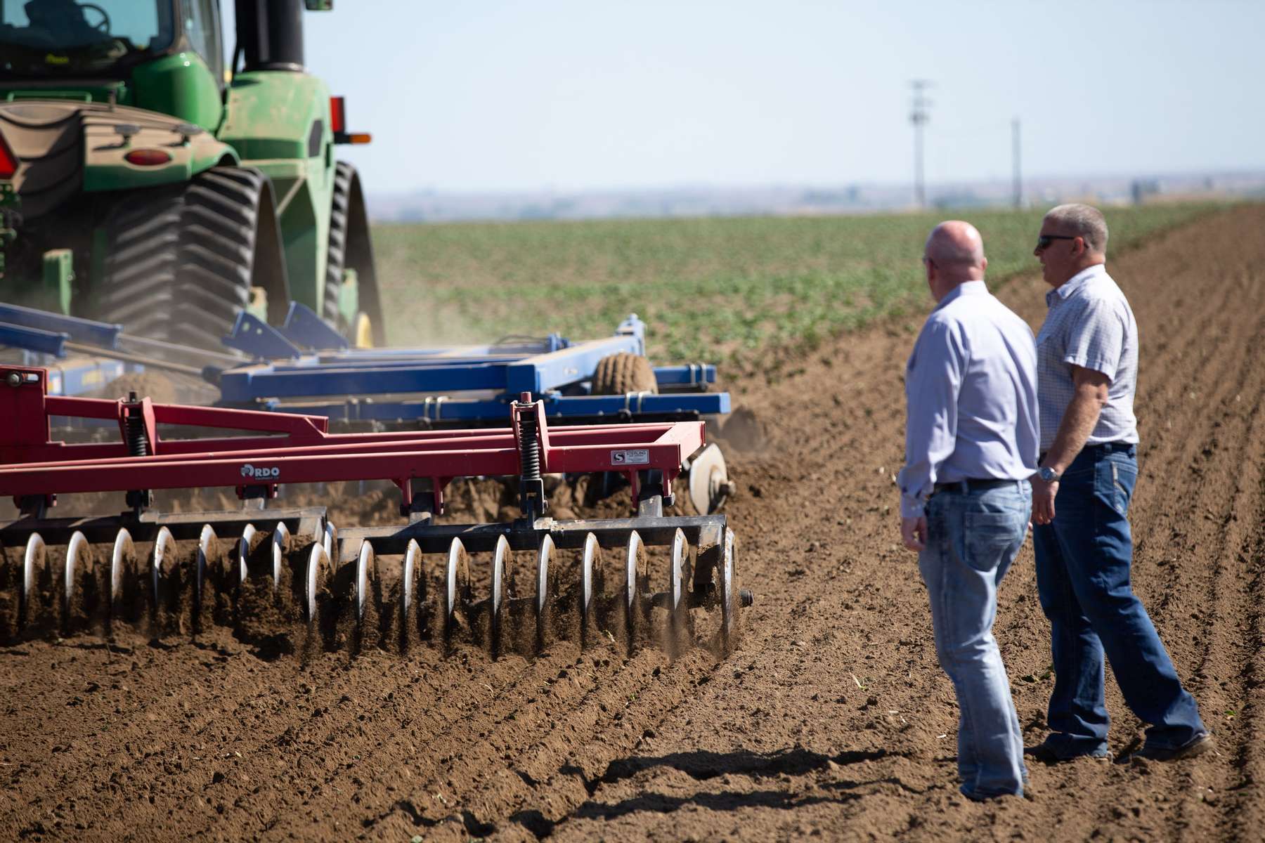 Dale Lathim, Executive Director of the Potato Grower’s of Washington and President of the Potato Marketing Association of North America (left) and grower Mike Pink of Pink Farms watch an agricultural machine destroy his potato plants in his field in Mesa, Washington on May 1, 2020. Pink had half his crop destroyed in order minimize his losses and plans to grow sweet corn there instead. A billion pounds of potatoes sits in excess in Washington state, the second largest potato producer in the country. About 70 percent of its crop usually goes to overseas, to Pacific Rim countries primarily, in the form of french fries, but with so many restaurants/food service closed in U.S. and internationally, they have way more potatoes than they can sell. Last year they didn’t have enough to meet demand; now growers are facing the prospect of losing it all. (photo by Karen Ducey)