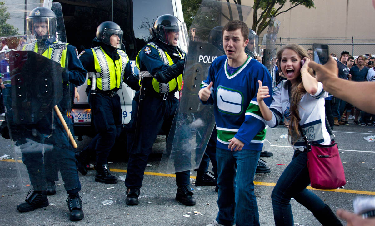 What's a party to some is serios business to others as Canuck's fans give a thumbs up police appear concerned of the growing riot on the downtown streets of Vancouver,BC after the Canucks were defeated by the Boston Bruins in the Stanly Cup on June 15, 2011. (photo copyright Karen Ducey)