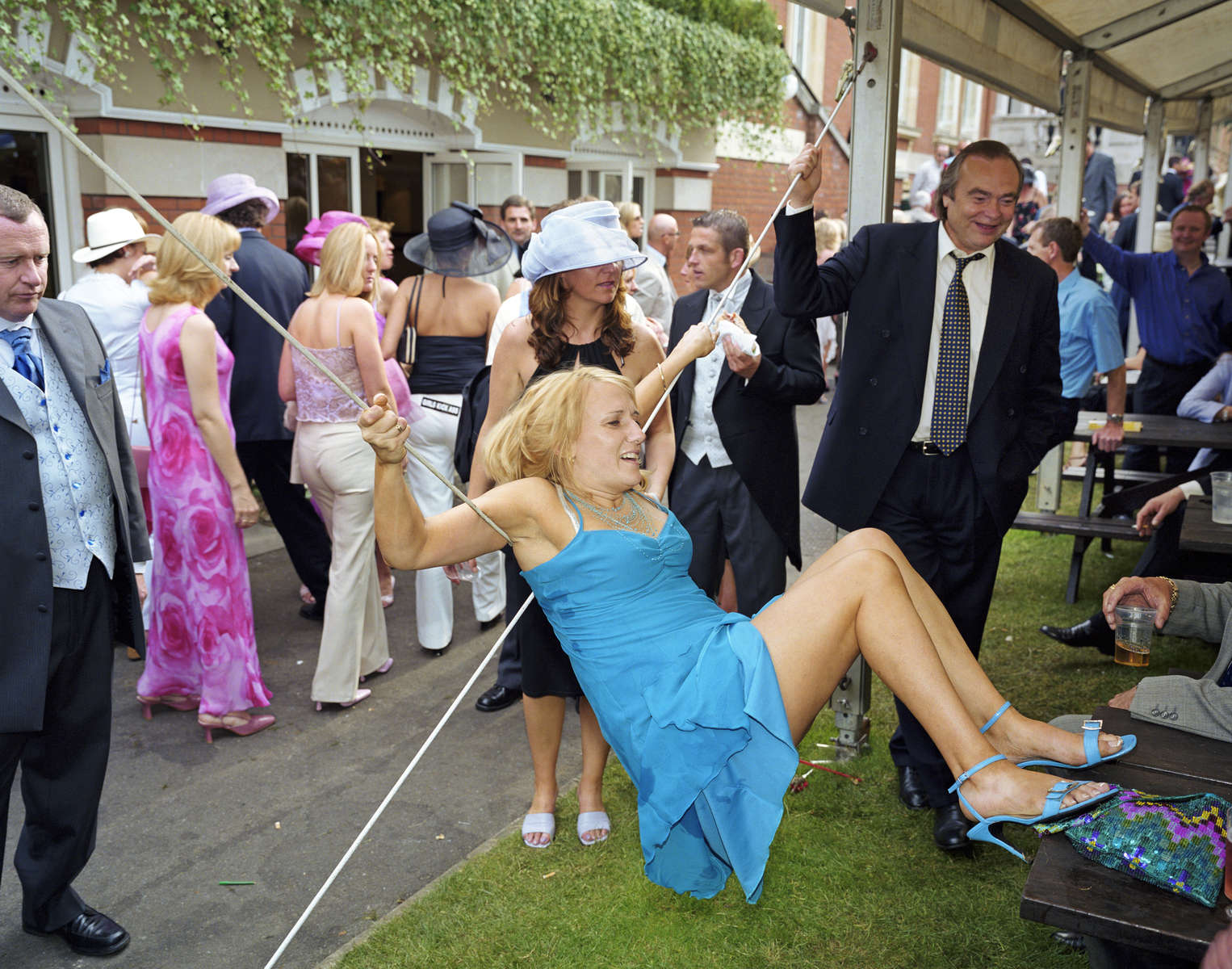 A female visitor to Royal Ascot hangs from the support of a hospitality tent. June 2002