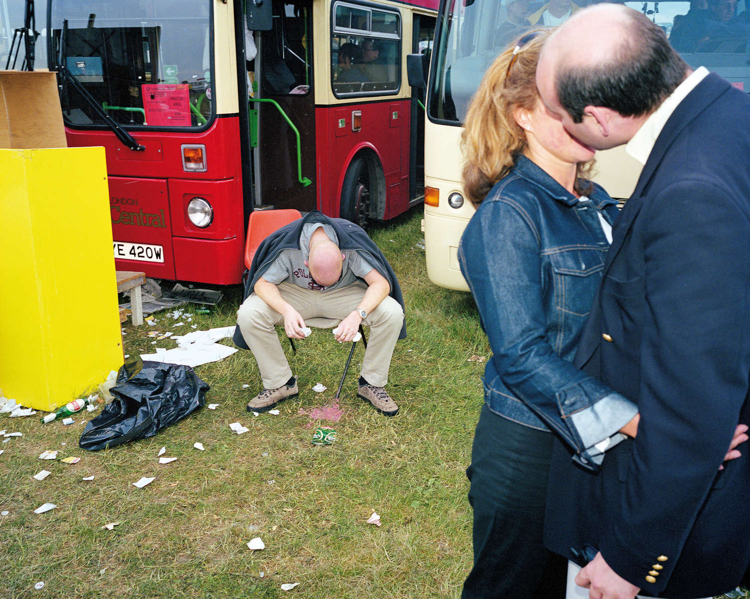 A couple kiss while a man vomits nearby on Derby Day at Epsom Downs Racecourse. June 2001