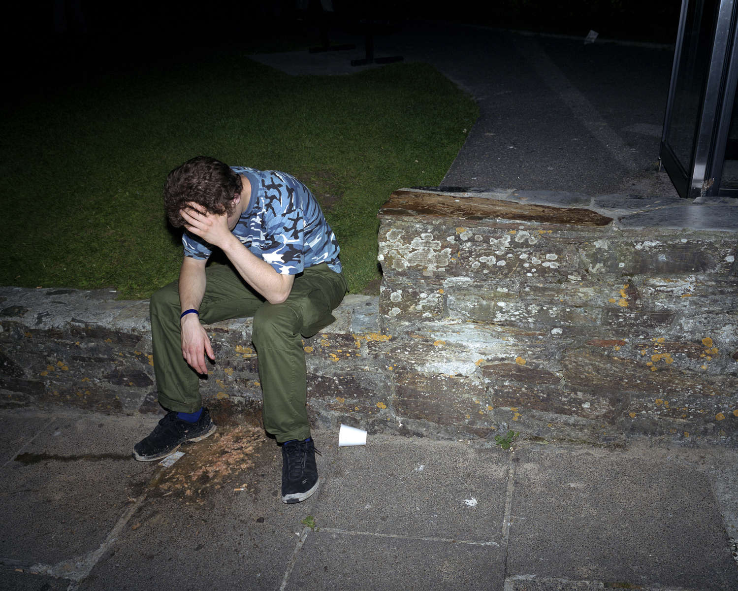 A young man sat on a wall feels the effects of a night out in Newquay, Cornwall. July 2001