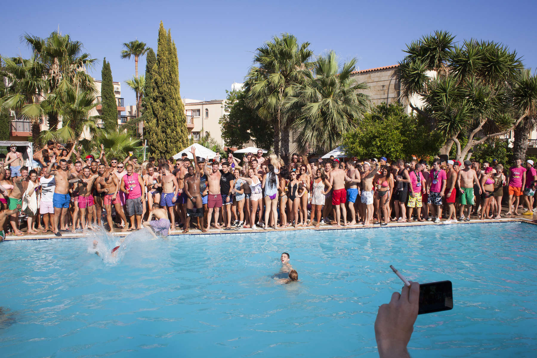 16:43 British seasonal workers and tourists in Ayia Napa, Cyprus, pose for a group photograph by the outside pool, during an afternoon pool party at Club Aqua.
