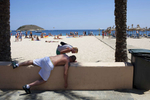 15:08 A Scottish woman checks on the well being of a British man slumped on a wall next to Magaluf beach, Majorca.