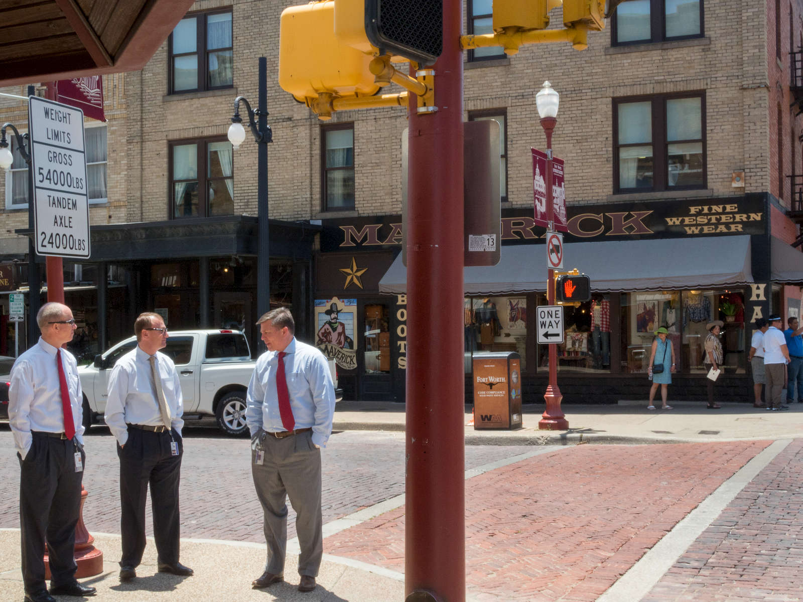 'FINE WESTERN WEAR' Businessmen chat on the corner of a street in the Stockyards district of Fort Worth.The Fort Worth Stockyards is a historic district that is located in Fort Worth, Texas, north of the central business district. The 98-acre (40 ha) district was listed on the National Register of Historic Places as Fort Worth Stockyards Historic District in 1976.They are a former livestock market which operated under various owners from 1866.Dallas is a major city in Texas and is the largest urban center of the fourth most populous metropolitan area in the United States. The city ranks ninth in the U.S. and third in Texas after Houston and San Antonio. The city's prominence arose from its historical importance as a center for the oil and cotton industries, and its position along numerous railroad lines.For two weeks in the summer of 2015, photographer Peter Dench visited Dallas to document the metroplex in his epic reportage, DENCH DOES DALLAS.Photographed using an Olympus E-M5 Mark II©Peter Dench/Getty Images Reportage