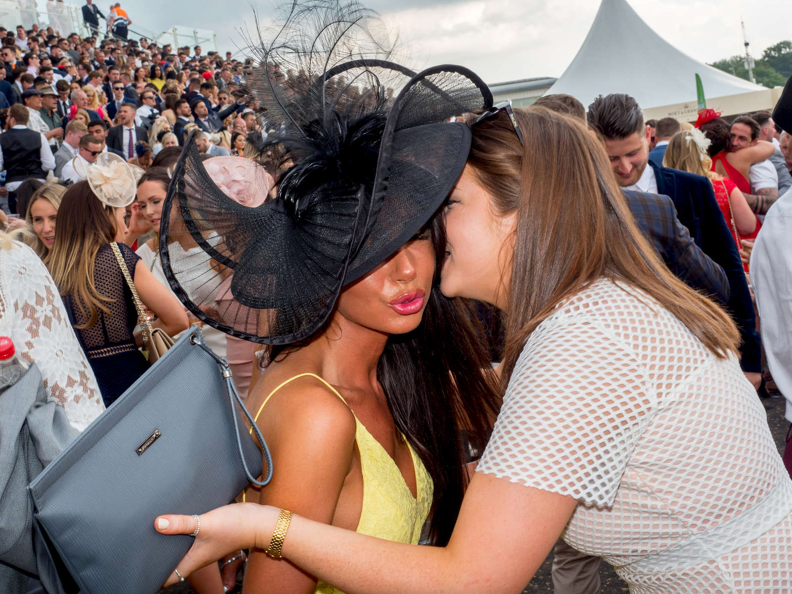 Two women greet each other among the crowd on Ladies' Day at Epsom.Ladies' Day is traditionally held on the first Friday of June, a multitude of ladies and gents head to Epsom Downs Racecourse to experience a day full of high octane racing, music, glamour and fashion.