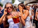 A young woman on her cell phone holds a jar of Pimm's.Ladies' Day is traditionally held on the first Friday of June, a multitude of ladies and gents head to Epsom Downs Racecourse to experience a day full of high octane racing, music, glamour and fashion.