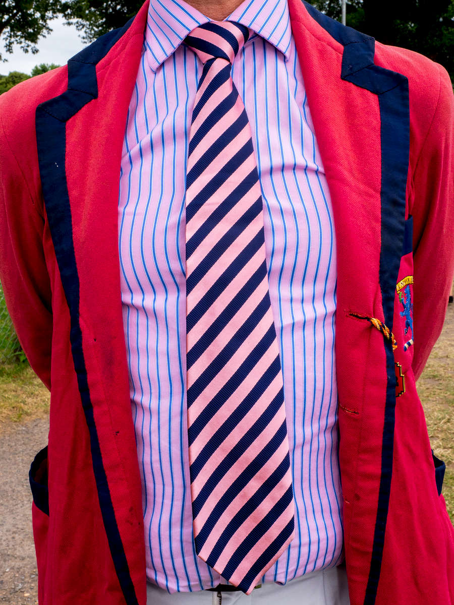 A man wearing the club tie and blazer of Emmanual Cambriddge Boat Club at Henley Royal Regatta, a rowing event held annually on the River Thames by the town of Henley-on-Thames, England. It was established on 26 March 1839.