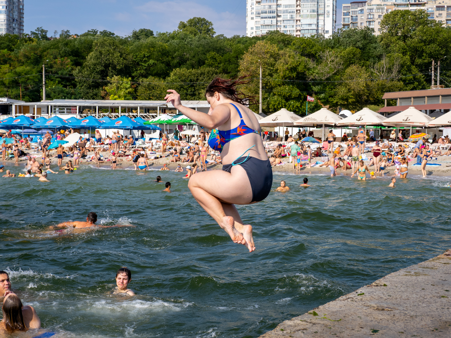 ODESSA, UKRAINE - AUGUST 26: Friends swim and jump into the sea on August 26, 2023 in Odessa, Ukraine. Several beaches in Ukraine's Black Sea city port of Odessa were officially reopened for swimming for the first time since the start of the Russian invasion, bathing remained banned during air raid alerts, an Anti-mine net was placed in between two piers to prevent swimmers encountering shallow-water mines many of which were dislodged by flood waters from the destruction of Kakhovka dam under control of the Russian military. The opening of the beaches has been a welcome respite from the tensions of war. (Photo by Peter Dench/Getty Images)