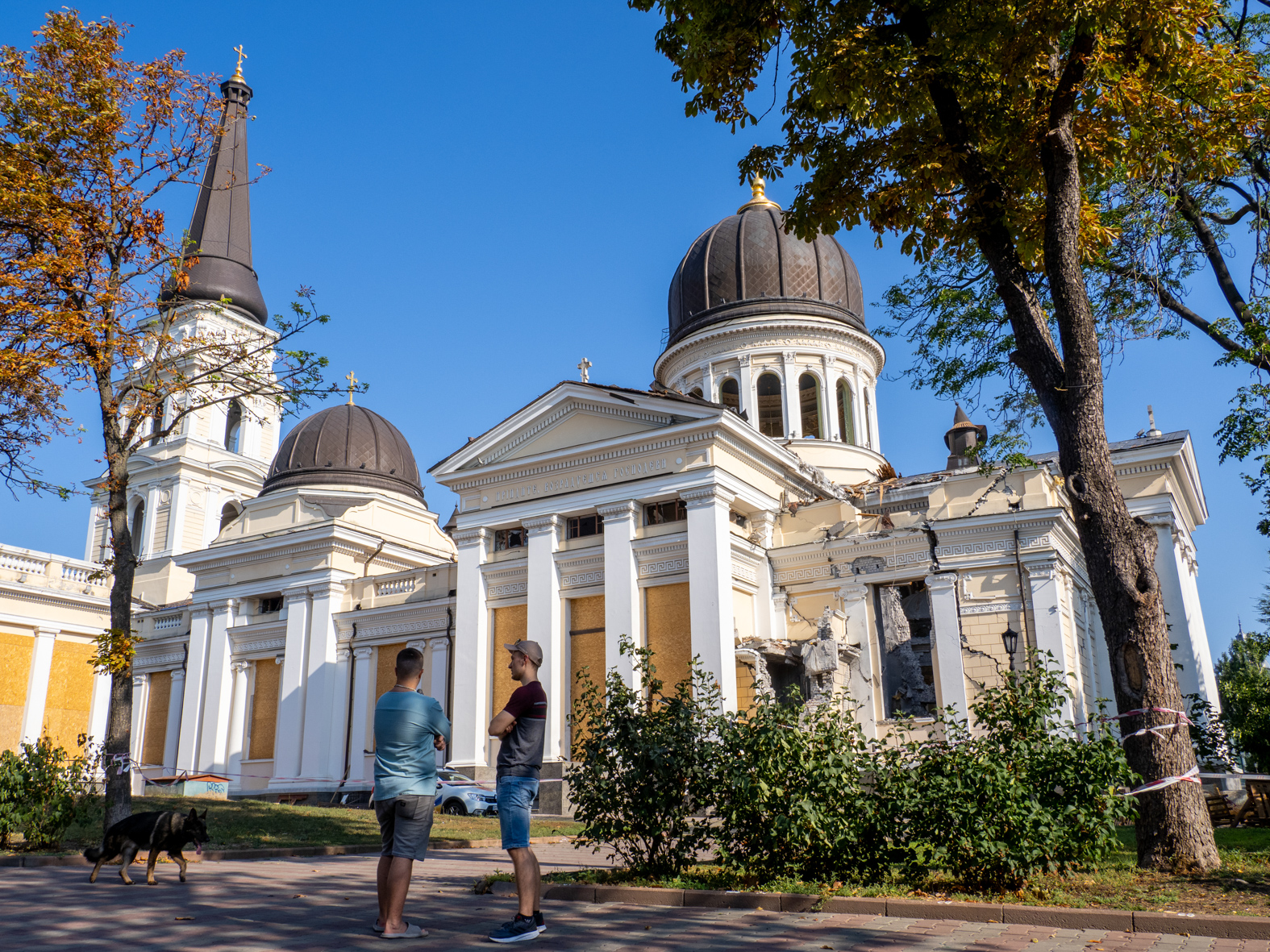 ODESSA, UKRAINE - AUGUST 27: Two men chat next to the Transfiguration Cathedral on August 27, 2023 in Odessa, Ukraine. In the early hours of July 23, a Russian missile strike, which killed one city resident and injured 20 others, reduced a large portion of the cathedral to rubble. (Photo by Peter Dench/Getty Images)