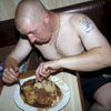 John Boy, a 22 year old geordie skinhead in 1999 tucking into a hearty meal of meat, potatoes and veg in the kitchen on board The Allegiance. In 1999, Photojournalist Peter Dench spent five  days onboard The Allegiance, a 60 foot UK Scarborough-based trawler, fishing the North Sea, with a crew of five.  The future has since become extremely bleak for the English trawler men; huge areas of the North Sea have been declared \'off limits\' and fishing quotas have been slashed in an attempt to rescue dwindling North Sea stocks from the point of extinction.  These measures have jeopardised the jobs of those in the industry and put dependent towns, like Scarborough, on the brink of ruin.Dench returned to The Allegiance in 2005 to be reunited with the crew and to find out how the decline of the North Sea fishing industry has affected their lives.