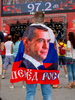 A fan with a flag featuring Dmitry Anatolyevich Medvedev, a Russian politician who has served as the Prime Minister of Russia since 2012. From 2008 to 2012, Medvedev served as the third President of Russia.The Moscow FIFA Fan Fest located at Vorobyovy Gory (Sparrow Hills) with a venue Capacity of 25,000. The site provides a spectacular view down the hill, directly towards Luzhniki Stadium and Moscow City. The 21st FIFA World Cup football tournament took place in Russia in 2018. It was the first World Cup to be held in Eastern Europe and the eleventh time that it has been held in Europe. For the first time the tournament took place on two continents – Europe and Asia. All but two of the stadium venues were in European Russia.