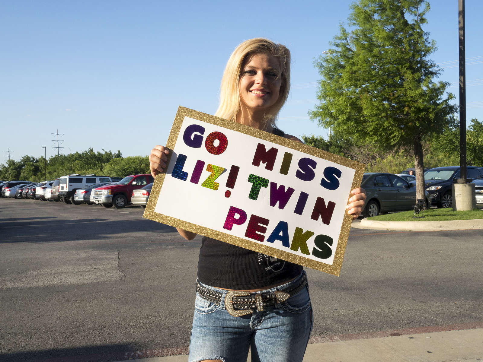 A visitor with a cheer card for Liz at the Twin Peaks 2015 National Bikini Contest where around 68 girls from the USA competed for the crown for Miss Twin Peaks 2015 at Gas Monkey Live Dallas on the 24th June.Twin Peaks is a chain of sports bars and restaurants (colloquially referred to as breastaurants) based in Dallas, Texas. The chain is known for having its waitresses dress in revealing uniforms that consist of cleavage- and midriff-revealing red plaid (or sometimes black bikini) tops, as well as khaki short shorts. At other times, waitresses wear revealing seasonal or themed outfits. Restaurants are decorated in the theme of a wilderness lodge and serve a mix of American, Southwest and Southern cuisines as well as alcohol. The chain's slogan is {quote}Eats. Drinks. Scenic Views.{quote}Dallas is a major city in Texas and is the largest urban center of the fourth most populous metropolitan area in the United States. The city ranks ninth in the U.S. and third in Texas after Houston and San Antonio. The city's prominence arose from its historical importance as a center for the oil and cotton industries, and its position along numerous railroad lines.For two weeks in the summer of 2015, photographer Peter Dench visited Dallas to document the metroplex in his epic reportage, DENCH DOES DALLAS.Photographed using an Olympus E-M5 Mark II©Peter Dench/Getty Images Reportage