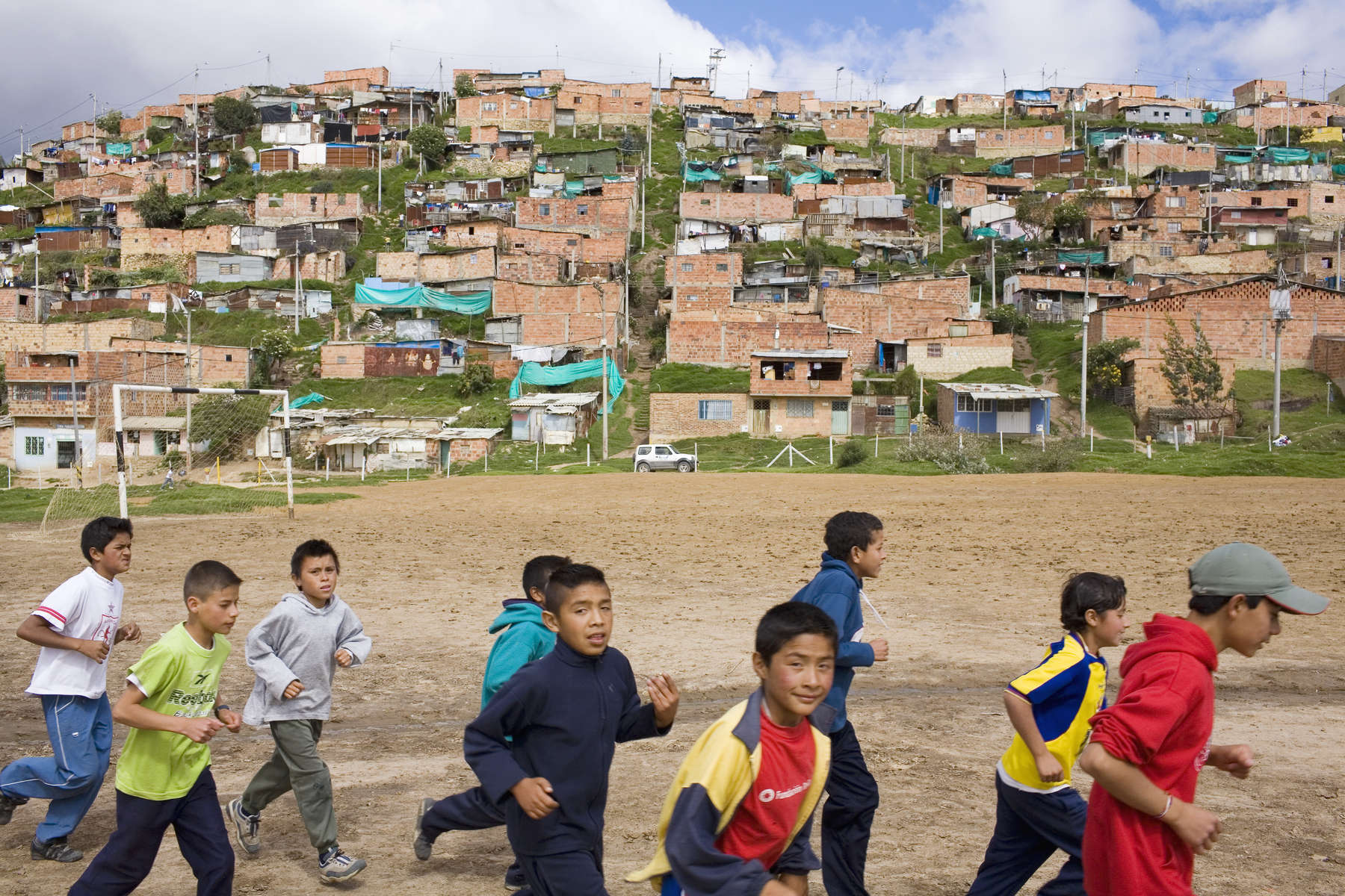 Children on the 'Goals For a Better Life' football programme train on a pitch at the foot of a slum on the outskirts of Bogota. Run by the 'Colombianito's' charity, it aims to use the kids passion for football to keep them in school and away from street gangs.In disaster areas, war zones and urban wastelands, football keeps humanity alive. It brings nations together and promotes unity. It encourages equality and generates pride and self-belief. It has the power to heal and to help, to motivate, to give freedom to dreams and empower a generation. There are millions of people playing the game or helping it to flourish who find that football brings a positive dimension to their lives.Away from the billionaire owned clubs with it's multi-million dollar players, Football's Hidden Story is a series of emotive human interest photographs showing the positive impact football has had at grassroot level on individuals and communities all around the world. 