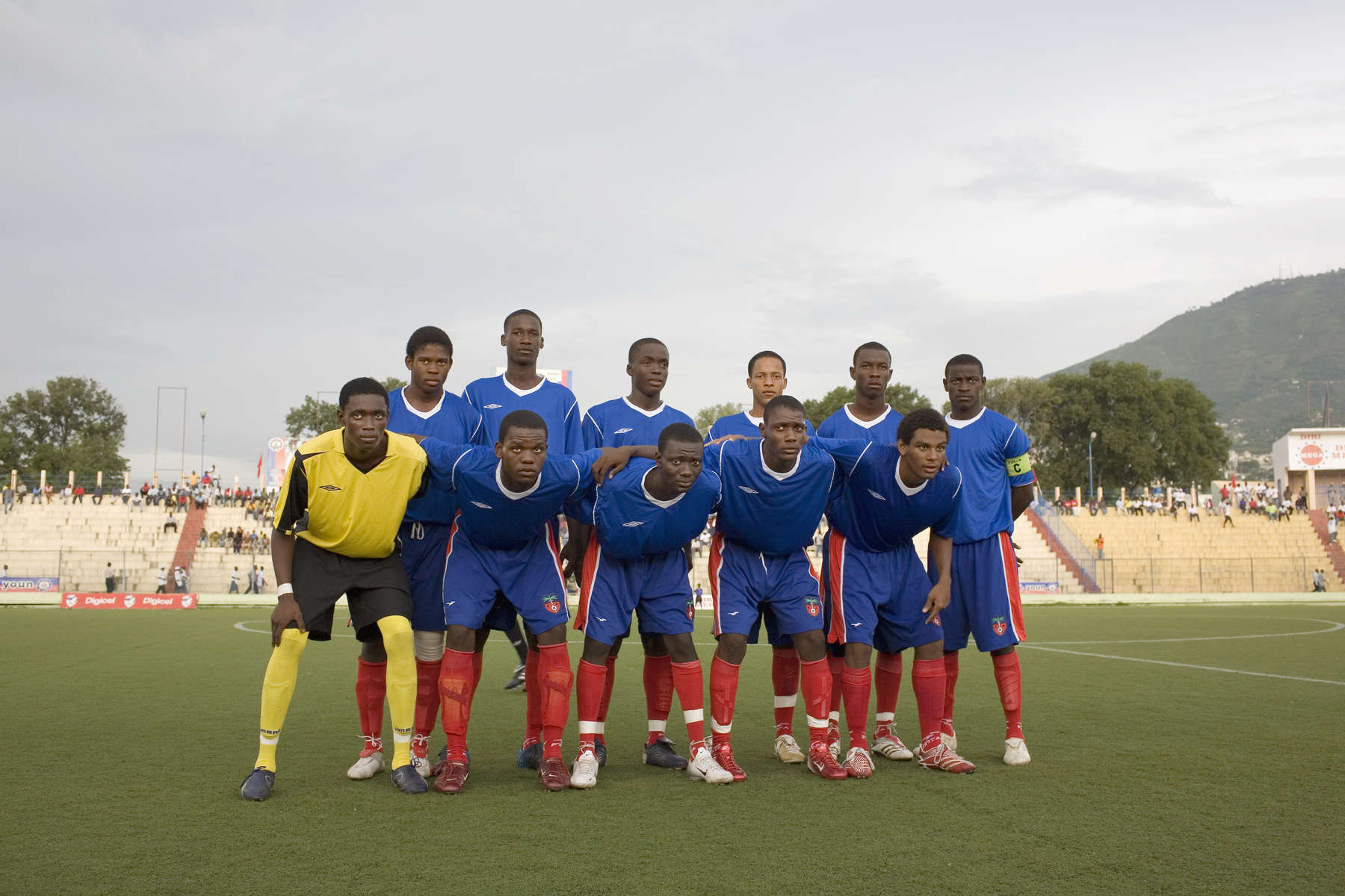 The Haitian under 17 team pose for a photograph before a match against the USA's Cleveland Cavalier's at the Sylvio Cator Stadium. They went on to win the game. In 1974 Haiti won a place at the World Cup Finals. 33 revolutionary years later the impoverished country's under 17 team played at the FIFA U-17 World Cup Finals in South Korea.In disaster areas, war zones and urban wastelands, football keeps humanity alive. It brings nations together and promotes unity. It encourages equality and generates pride and self-belief. It has the power to heal and to help, to motivate, to give freedom to dreams and empower a generation. There are millions of people playing the game or helping it to flourish who find that football brings a positive dimension to their lives.Away from the billionaire owned clubs with it's multi-million dollar players, Football's Hidden Story is a series of emotive human interest photographs showing the positive impact football has had at grassroot level on individuals and communities all around the world. 