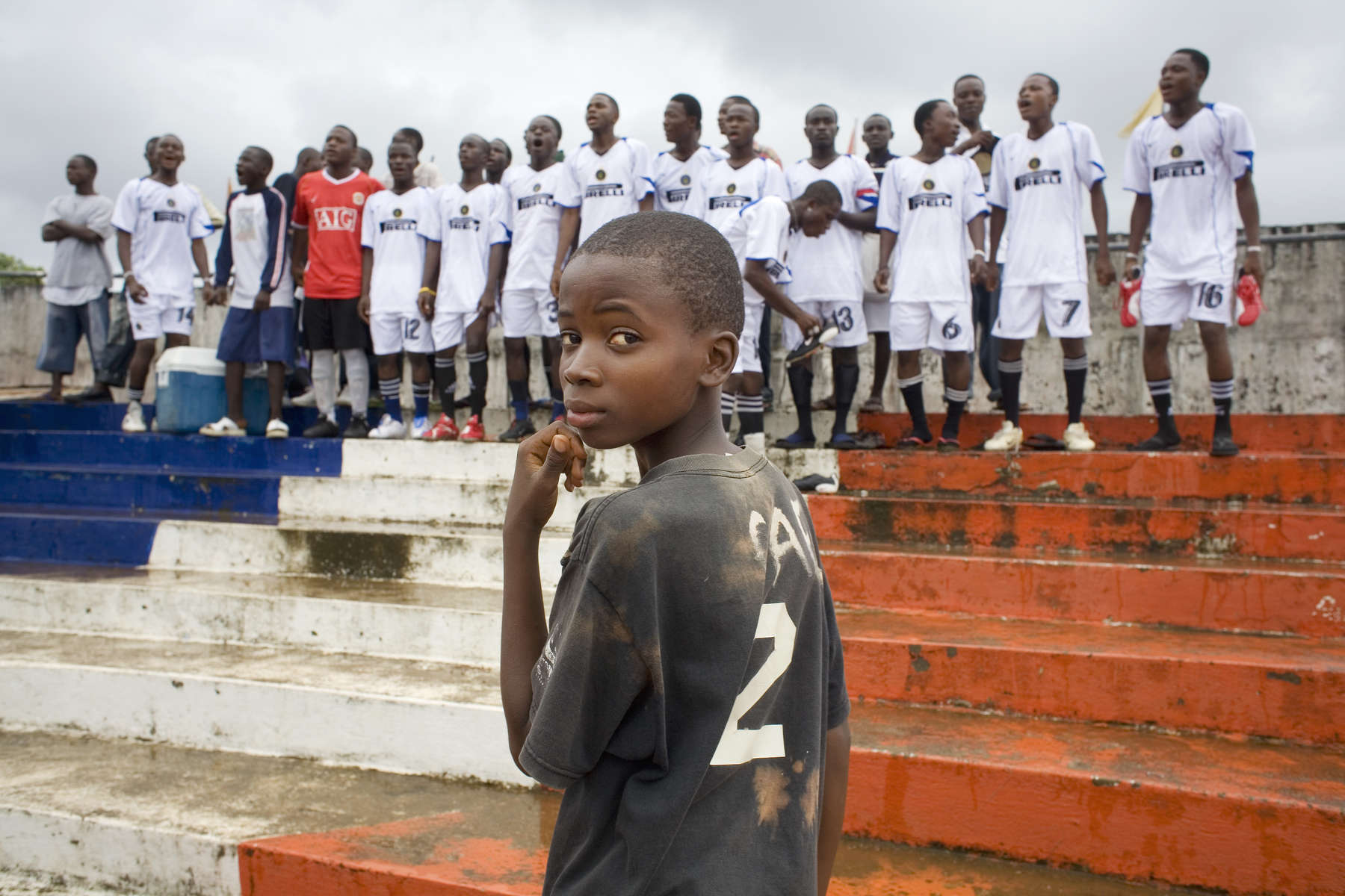 A football team sing inspirational songs from the terraces of the Antoinette Tubman Stadium, Headquarters of the Liberian Football Association. After over a decade of civil war, football is helping bring communities back together.In disaster areas, war zones and urban wastelands, football keeps humanity alive. It brings nations together and promotes unity. It encourages equality and generates pride and self-belief. It has the power to heal and to help, to motivate, to give freedom to dreams and empower a generation. There are millions of people playing the game or helping it to flourish who find that football brings a positive dimension to their lives.Away from the billionaire owned clubs with it's multi-million dollar players, Football's Hidden Story is a series of emotive human interest photographs showing the positive impact football has had at grassroot level on individuals and communities all around the world. 