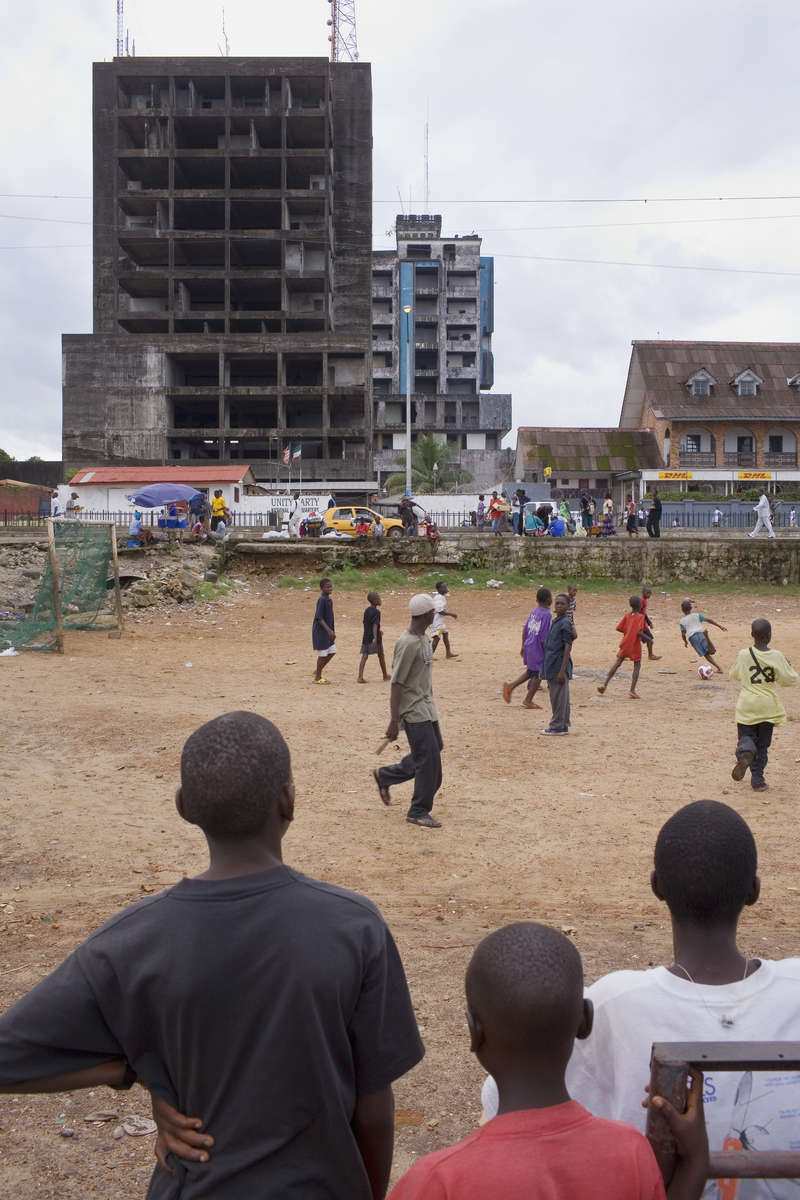 Kids play football in front of a burnt out building in the Liberian capital Monrovia. After over a decade of civil war, football is helping bring communities back together.In disaster areas, war zones and urban wastelands, football keeps humanity alive. It brings nations together and promotes unity. It encourages equality and generates pride and self-belief. It has the power to heal and to help, to motivate, to give freedom to dreams and empower a generation. There are millions of people playing the game or helping it to flourish who find that football brings a positive dimension to their lives.Away from the billionaire owned clubs with it's multi-million dollar players, Football's Hidden Story is a series of emotive human interest photographs showing the positive impact football has had at grassroot level on individuals and communities all around the world. 