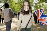 A young girl with a Kate Middletom mask on the back of her head waves a union flag as she walks along the Mall towards Buckingham Palace.