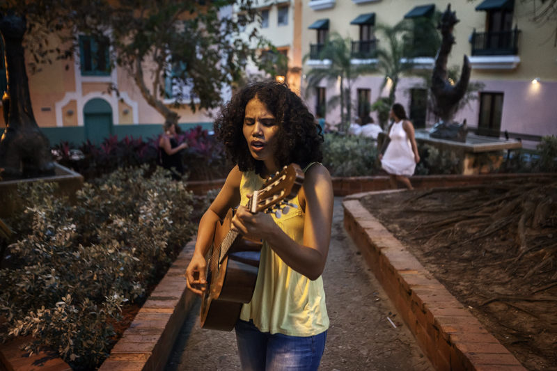 A young girl is playing guitar in the tiny streets of Old San Juan.