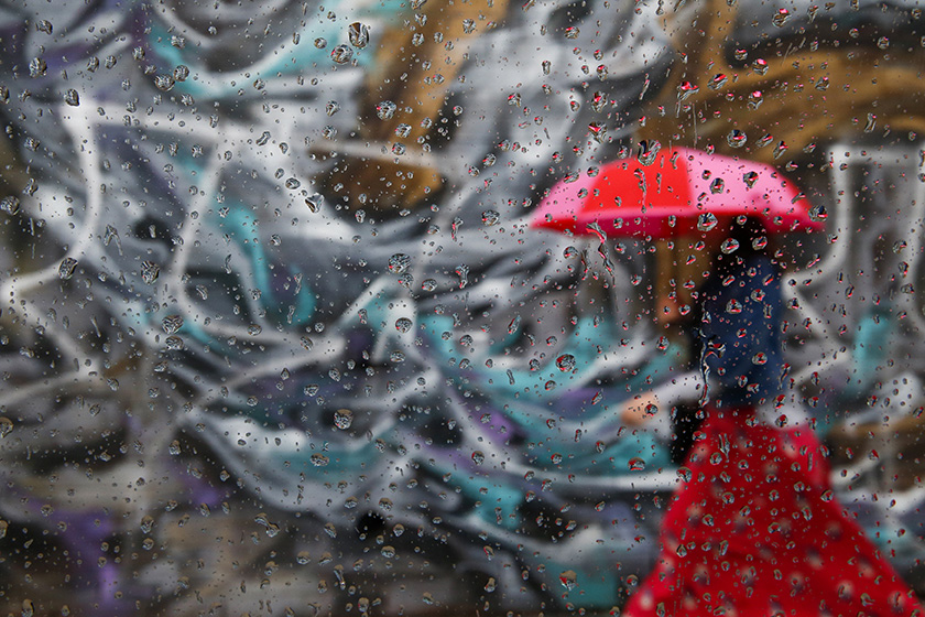 A woman is seen walking by graffiti on a wall in the Williamsburg neighborhood of the borough of Brooklyn in New York, September 16, 2014. The photo was take through raindrops on the window of car. REUTERS/Shannon Stapleton (UNITED STATES 