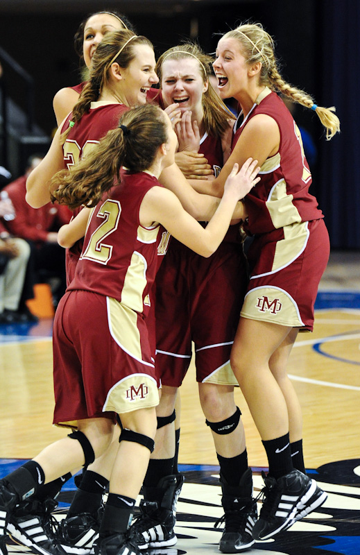 Ashlynn Spahn, front left, Tori Schickel, left center, Brianna Dickerson, back left, and Casey Jochem, right, surround Maura Muensterman, center, after she made the game winning shot in overtime against Fort Wayne Bishop Luers in the 2A girls' state championship basketball game at the Hulman Center in Terre Haute, on Saturday, March 3, 2012.  Muensterman's shot left 0.2 seconds on the clock. Bishop Luers then called a time out when they had no timeouts remaining, resulting in a two-shot technical foul. Muensterman made the two free throws to end the game with a final score of 56-52.