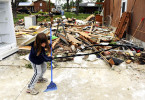 Whitney Johnson, 6, cleans up around some of the destruction at her grandmother's home at 106 S. Weber Drive in Haubstadt, Ind. Family members believe a tornado hit the home when a line of severe storms blew through the area the night before. 