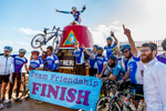 A group of bicyclists celebrate at the Southernmost Point marker after riding from Miami