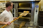 Baker Nick taking fresh baked bread out of the oven at Bracken Mountain Bakery