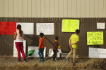 Gaby Camacho, left, and her three younger brothers, from the left, Angel, Julio and Israel read over the signs posted on the fence near the site 13-year-old Andy Lopez was shot and killed by a Sonoma County Sheriff's deputy in Santa Rosa on Friday, October 25, 2013. (Conner Jay/The Press Democrat) 