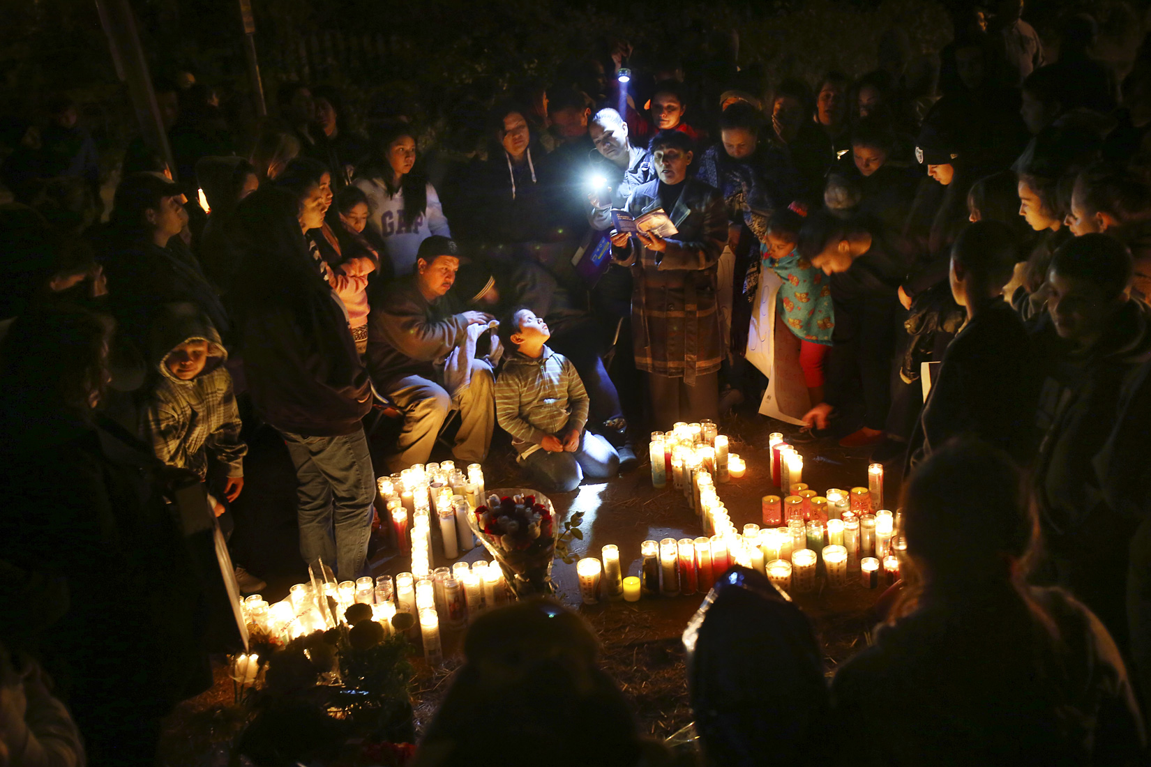 Sujey Lopez and her husband Rodrigo Lopez, center, sit with their son Randy while praying at the site where their 13-year-old son Andy Lopez was shot and killed by a Sonoma County sheriff's deputy near the corner of Moorland and West Robles avenues in Santa Rosa, October 23, 2013. (Conner Jay/The Press Democrat) 