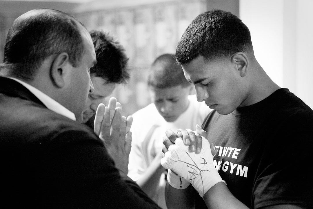 Eric Prado, right, prays with family before his fight in the Central Coast Throwdown at Palma High School. 