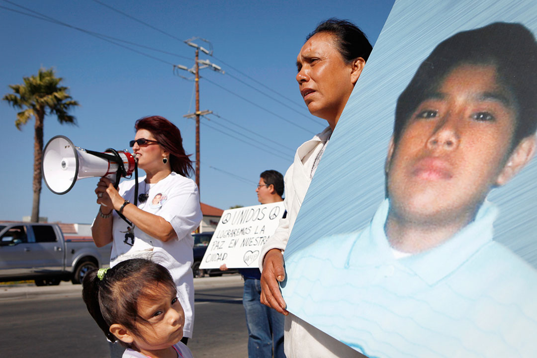 Flora Cristobal holds a picture of her 15-year-old son Rodolfo Cristobal while her daughter looks at a picture of her late brother during a peace rally August 1, 2010 in Salinas. Rodolfo was shot and killed in a gang related shooting last October 14, 2009 on Archer Street in Salinas
