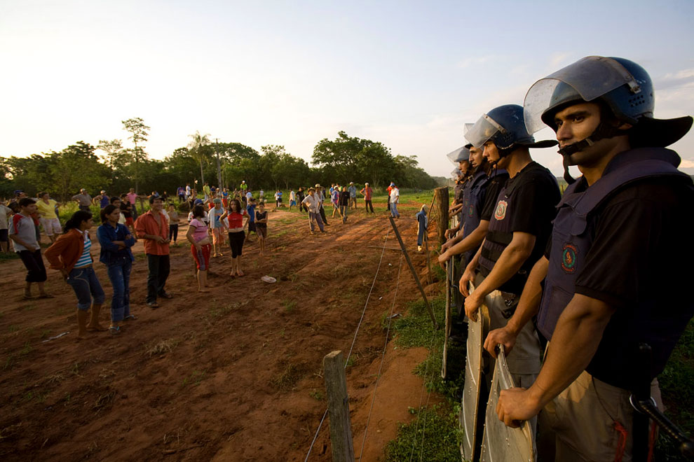 San Marcos, San Vicente district, San Pedro--October 27, 2008--National police stand guard at the edge of a Brazilian-owned genetically modified soybean farm, after a court-ordered eviction of a landless farmers' settlement on the edge of the property. Peasant farmers’ demands for land have increased since a soy-farming boom gathered pace five years ago in Paraguay. A wave of land takeovers is sweeping the nation, putting the $600 million dollar transnational soy industry in Paraguay at risk, which represents more than 30 percent of total exports for the country. Soy production has increased exponentially in recent years due to rising demand worldwide for meat and cattle feed, and the booming biodiesel industry. Industrial soy is directed toward these markets. Most of the soybean producers are Brazilian and Argentinian who moved to Paraguay in the last 10-15 years. Of the current 600,000 soybean producers in Paraguay, only 24% are Paraguayan.