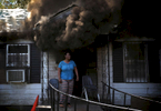 April 24, 2016 - A woman stands of the porch of a home in the 2800 block of Barron in Orange Mound as heavy smoke pours out of the front door and flames were visible in the back of the house while waiting for fire fighters to arrive. The residents, including a man in a wheel chair, escaped the home without injuries. (Mike Brown/The Commercial Appeal)