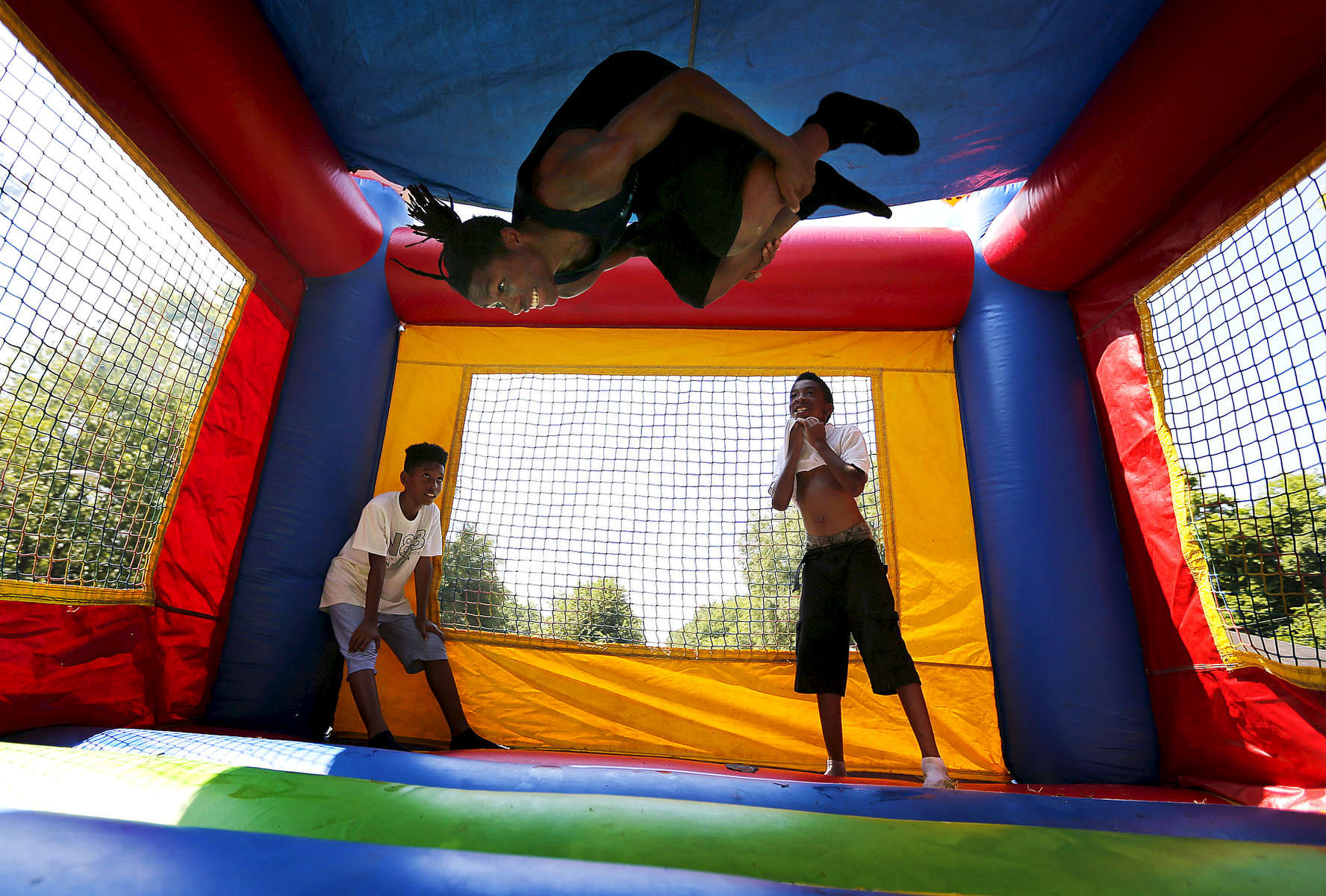 July 18, 2016 - Jim Brown (center), 15, flips inside a bounce house as Martekuz Harris (left), 12, and Jevon Jones, 11, look on during a {quote}Not in My Neighborhood{quote} block party hosted by DeAndre Brown and LifeLine 2 Success. The gathering took place down the street from where a 19-year-old was murdered on the 3500 block of Gowan, as a way to speak out against violence in the community. (Mike Brown/The Commercial Appeal)