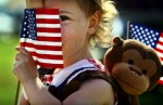 Briley Whitehead, 2, of Baileyton, AL, plays peekaboo from behind her flag in Tom Lee Park while waiting for the big fireworks display to light up the sky on the Fourth of July. (Mike Brown/Memphis Commercial Appeal)