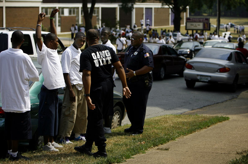 Jimmy Chambers, 44, an investigator for the Shelby County DA's gang unit, and MPD officer M.A. LeSure confront young men believed to be FAM members outside Trezevant High School. At least one is not a student there. Chambers says gang members routinely arrive around campuses at the end of the school day. {quote}They wear school uniforms,{quote} Chambers says, {quote}so they can blend in with the rest of the crowd.{quote} (Mike Brown/ Memphis Commercial Appeal)