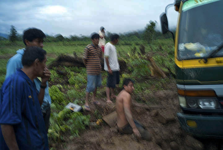 After a heavy rainfall, a group of Awajun men contemplate how to extract their vehicle from mud.
