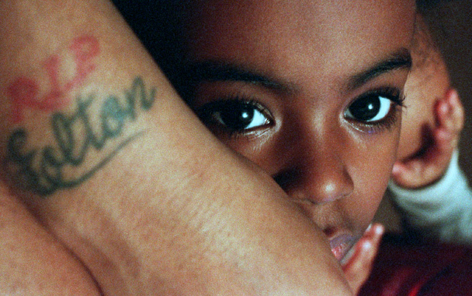Macquala McCormick, 5, is enveloped by her mother whose tattoo memorializes Macquala's father; he was shot to death.